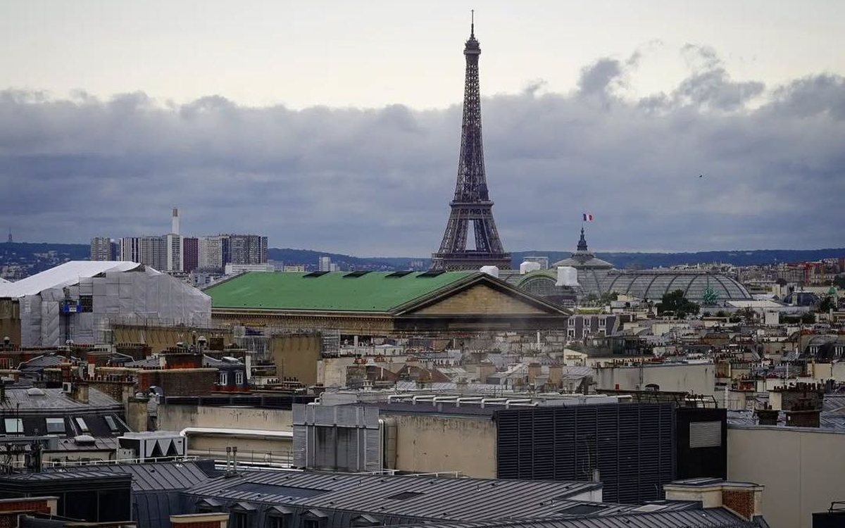 City rooftops at dusk with a famous iron tower rising in the distance.